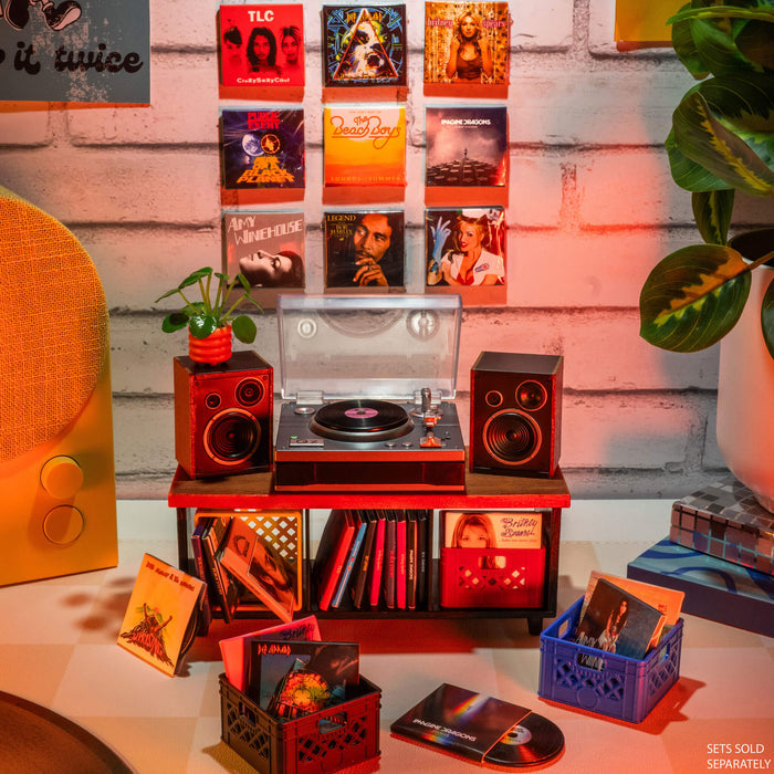 Mini record player setup with mini records and speakers on a wooden surface against a brick wall.