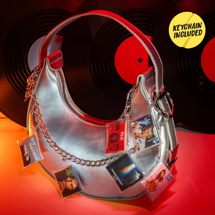 Metallic crescent-shaped bag with attached Mini vinyl keychains on a red and black background
