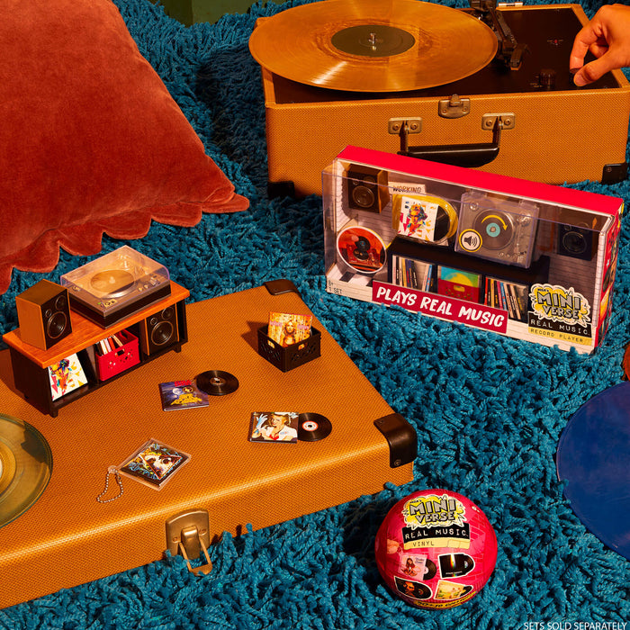 Mini Vintage record player with mini vinyl records and a retro-style music box on a textured blue surface.