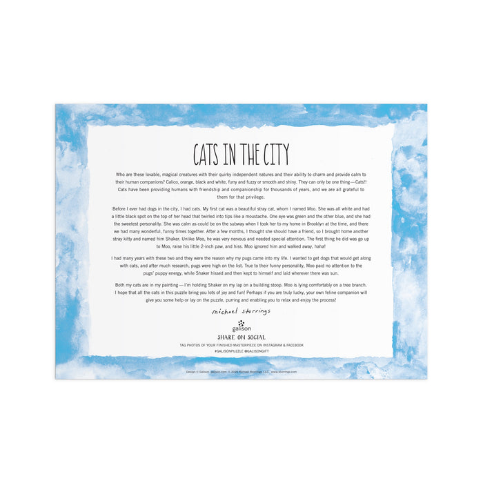 A white card with a blue cloud border and Michael Storrings Cats in the City 1000 Piece Puzzle at the top. Ideal for puzzle lovers, it showcases city cats and invites you to share your completed puzzle photos on social media.