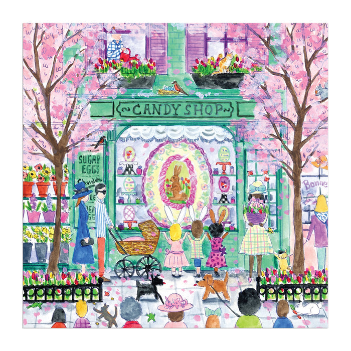 The Michael Storrings Easter Candy Shop 500 Piece Puzzle features a vibrant spring scene with children, adults, a dog, and a baby stroller admiring treats under blooming cherry blossoms.