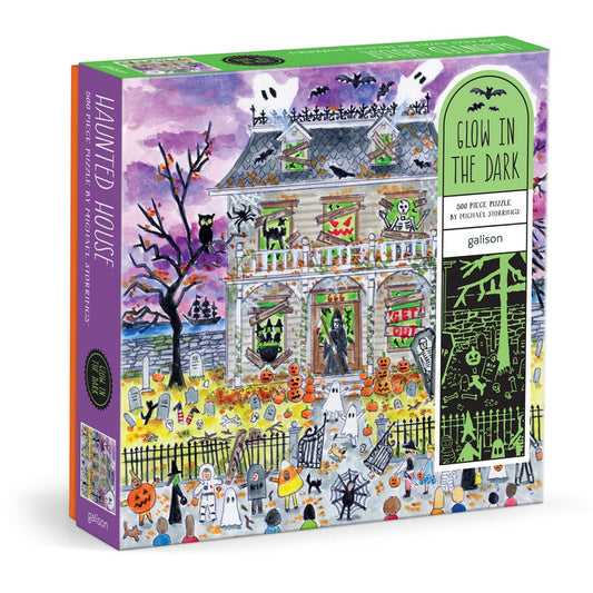 The Michael Storrings Haunted House 500 Piece Glow in the Dark Puzzle features ghosts, pumpkins, skeletons, and bats—perfect for intermediate puzzlers and branded by Michael Storrings.