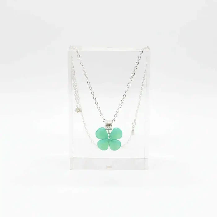 Mint green beaded clover necklace displayed in a clear stand, featuring Czech glass beads and sterling silver.