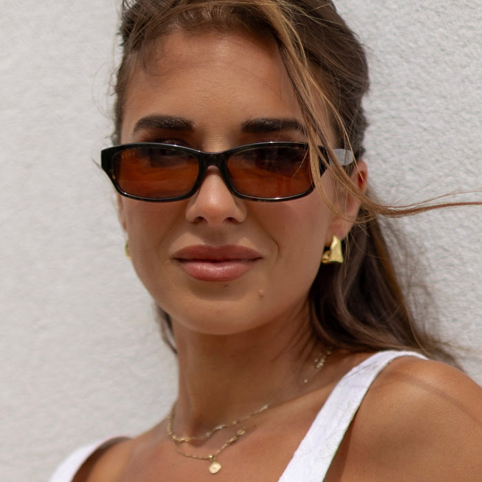 lifesytle - female wearing diff eyewear x jessie james decker misty square sunglasses with a koa tortoise brown acetate frame and brown lenses front view