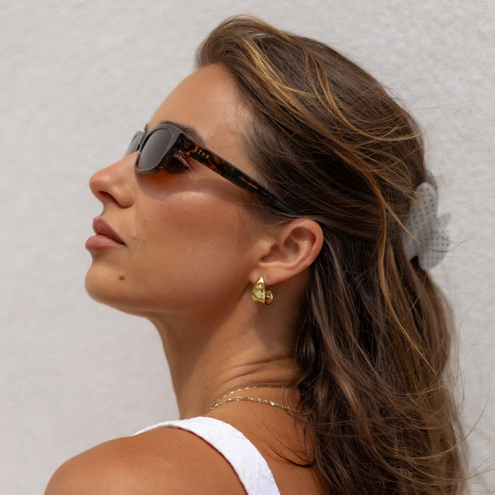 lifesytle - female wearing diff eyewear x jessie james decker misty square sunglasses with a koa tortoise brown acetate frame and brown lenses side view