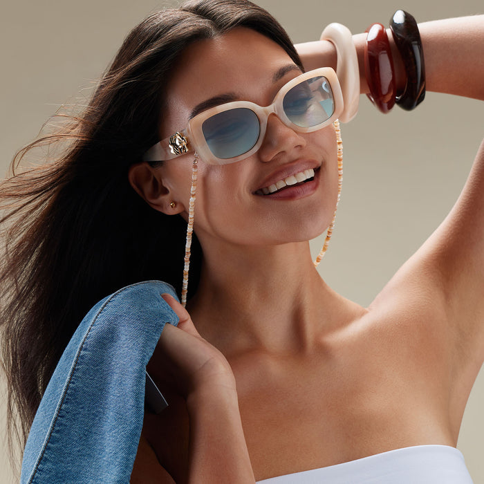 lifestyle - female wearing diff eyewear x disney princess featuring the moana square sunglasses with a beige tortoise acetate frame and seafoam green lenses angled view