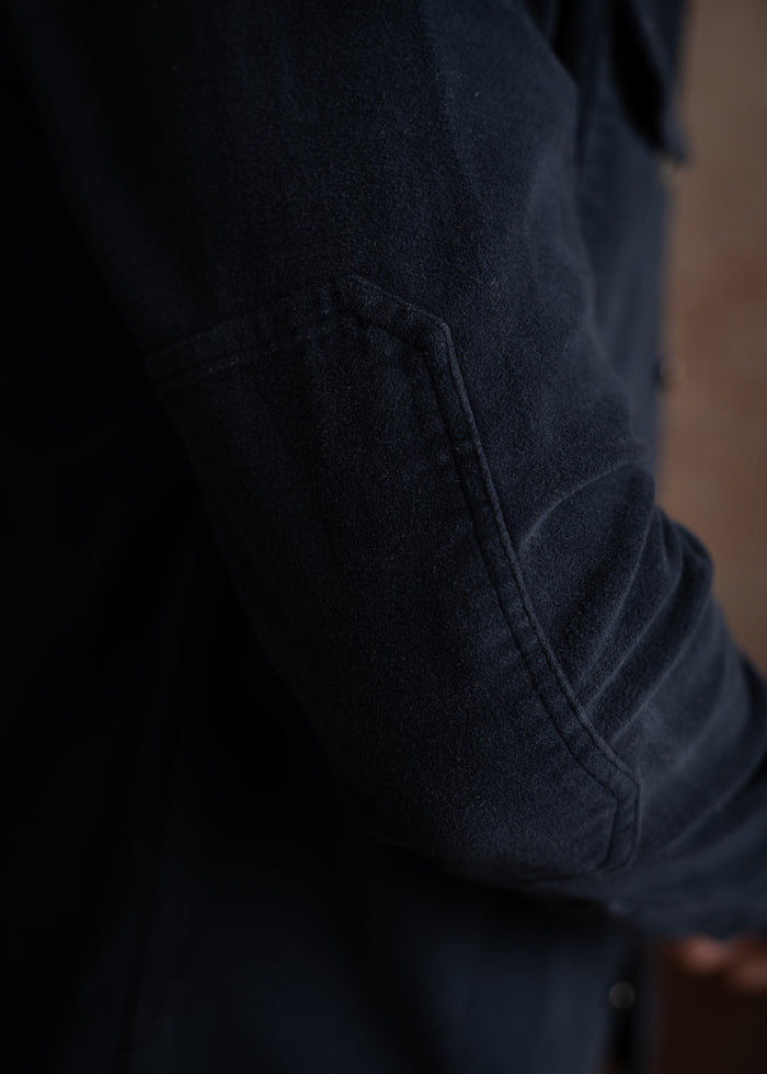 Close-up of a navy blue jacket sleeve with visible stitching and texture, highlighting the fabric's detail and craftsmanship.