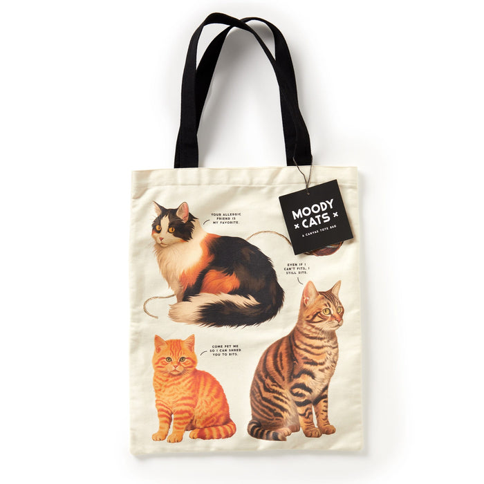 The Brass Monkey Moody Cats Canvas Tote is a cream tote with black handles, showcasing three illustrated cats, each with a funny personality description and a MOODY CATS tag—perfect for cat lovers with a sense of humor.