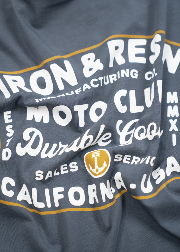 Close-up of a blue shirt with white text: "Iron & Resin Moto Club Durable Goods California, USA" and a yellow anchor logo.