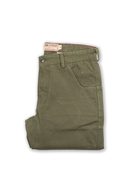 Olive green pants folded neatly, featuring a button closure and side pocket. Visible "Iron & Resin" label on the waistband.