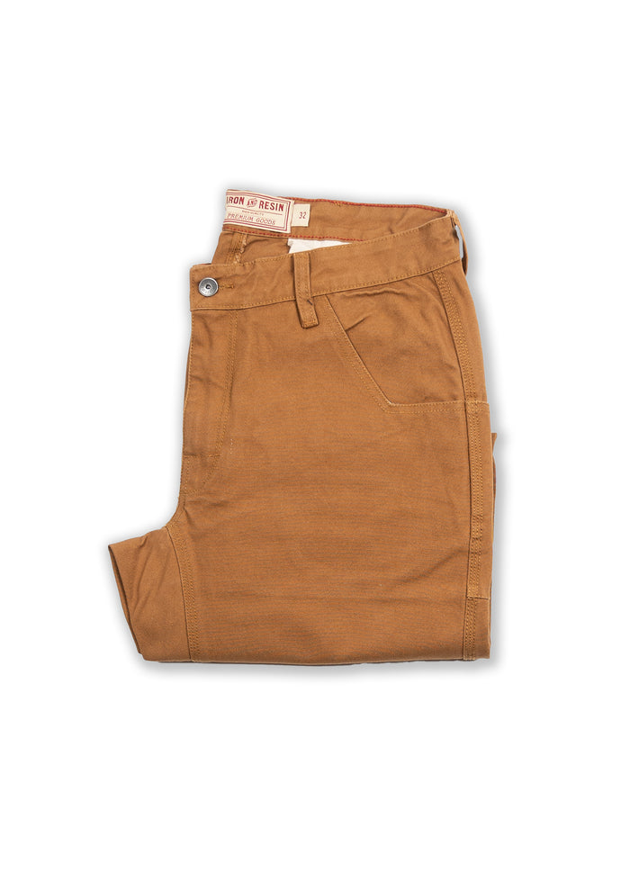 Folded brown pants with a button, pocket detail, and Iron & Resin label, size 32, on a white background.