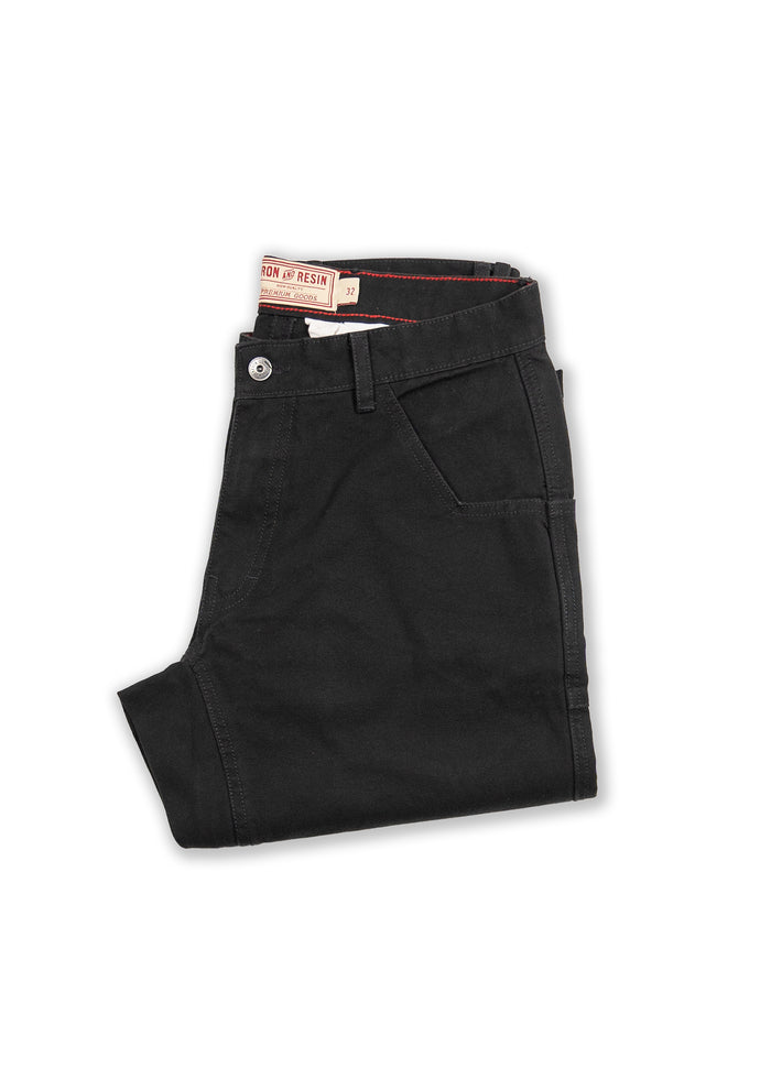 Folded black pants with a visible Iron and Resin label, showcasing sleek design and craftsmanship on a white background.