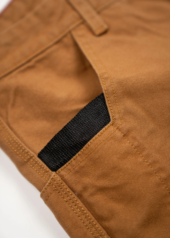 Close-up of brown pants pocket with a black fabric detail, highlighting the stitching and texture of the material.