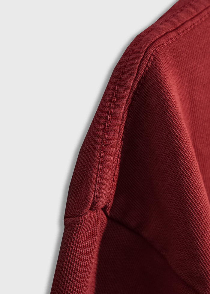 Close-up of a red fabric corner with visible stitching, showcasing texture and detail against a plain white background.