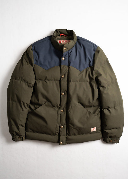Green and navy puffer jacket with button closure, featuring two front pockets, displayed against a plain white background.