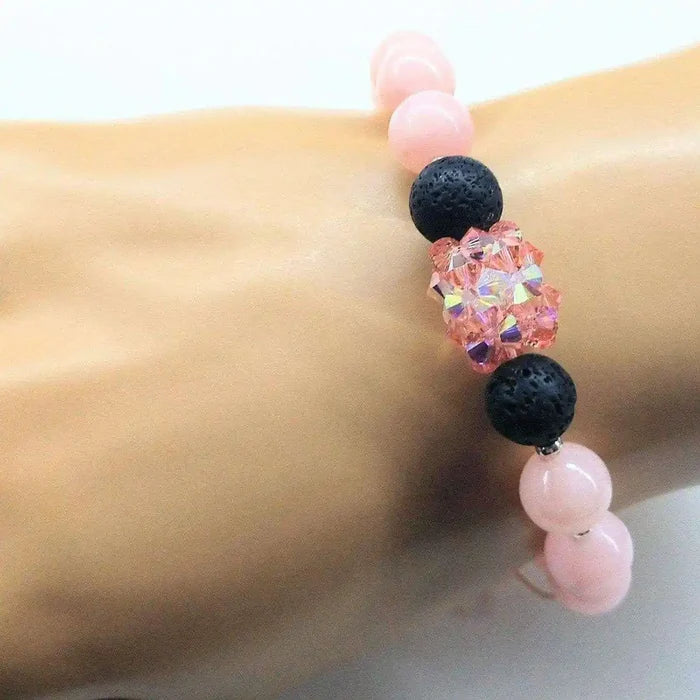 Peach Corral Jade Gemstone Crystal Lava Rock Bracelet displayed on a hand, showcasing its unique design with lava rock and pink beads.