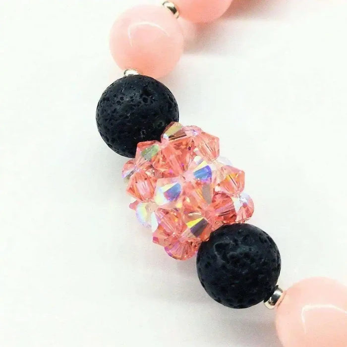 Close-up of Peach Corral Jade Gemstone Crystal Lava Rock Bracelet with pink and black beads.