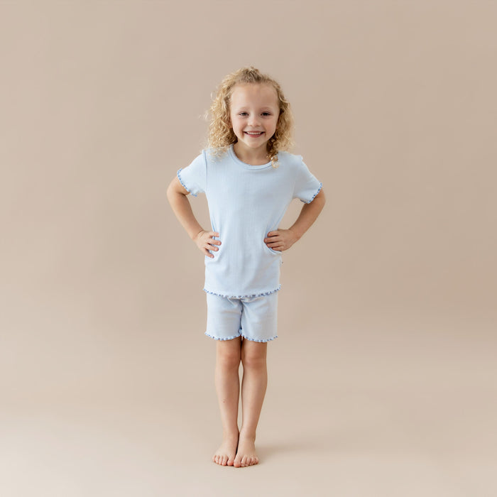 Young girl wearing a light blue pointellle lounge set on a beige background