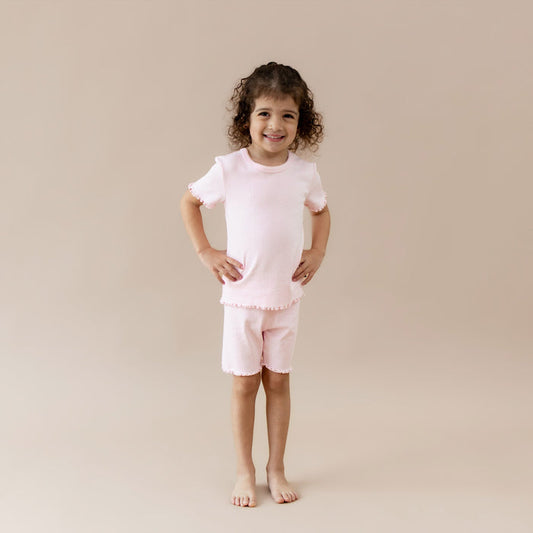 Child wearing a pink pointelle lounge outfit on a beige background