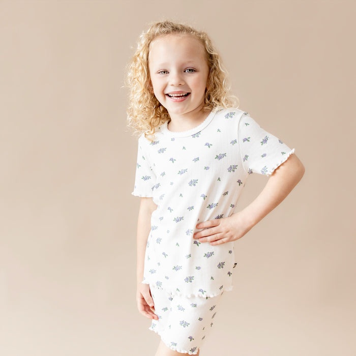 Child wearing a white shirt with small rose patterns on a beige background