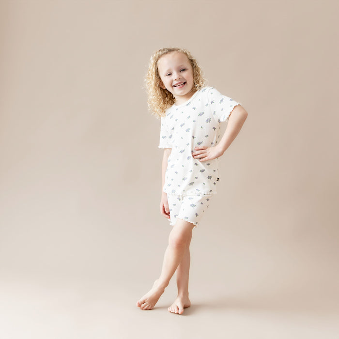 Young girl wearing a white outfit with small rose patterns on a beige background