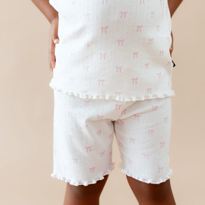 White lounge set with pink bow pattern on a beige background