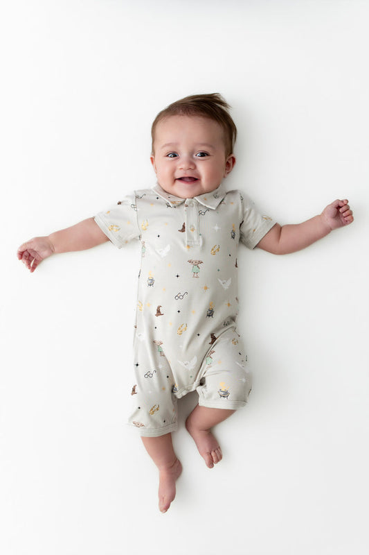 Baby wearing a Harry Potter patterned cream polo shortall on a white background
