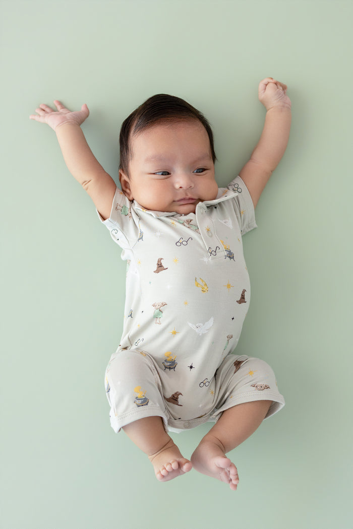 Baby wearing a polo shortall with Harry Potter prints on a cream fabric