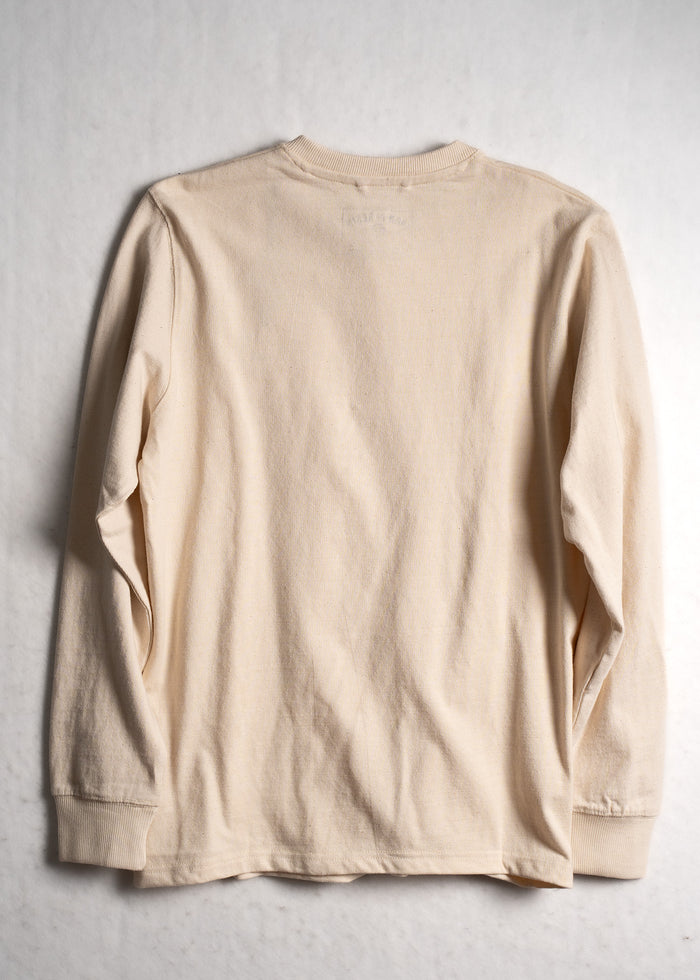 A beige long-sleeve shirt is laid flat on a light background, showcasing its simple design and ribbed cuffs.
