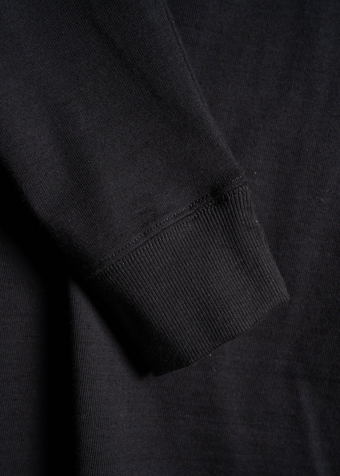 Close-up of a black sweatshirt sleeve showing ribbed cuff detail, highlighting the texture and fabric quality.