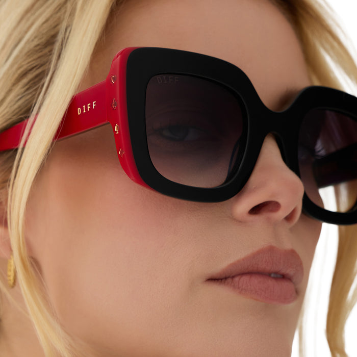 on model - female wearing diff eyewear x disney alice in wonderland queen of hearts square oversized sunglasses close up view of side details