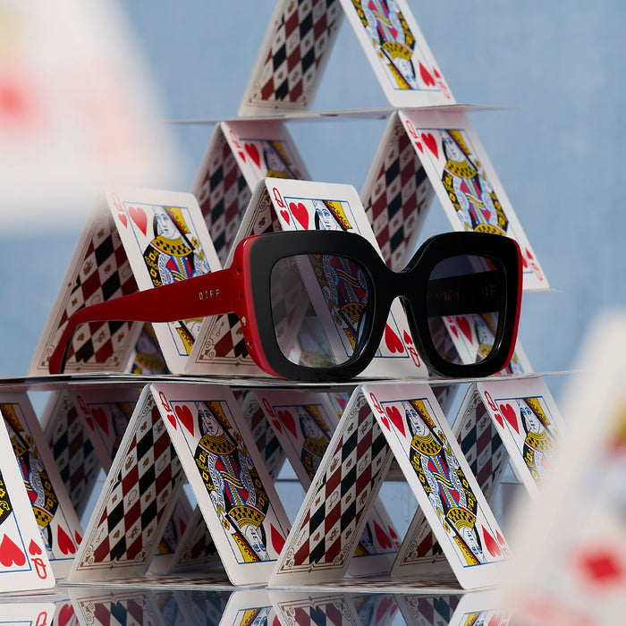 still life - diff eyewear x disney alice in wonderland queen of hearts square oversized sunglasses laying on a house of cards