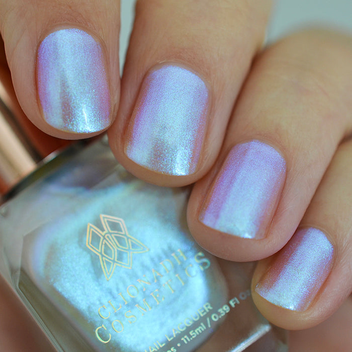 Close up shot of nails done with Radiance nail lacquer on medium skin tone holding the nail lacquer bottle