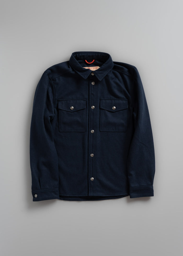 Navy blue button-up shirt with two chest pockets and a collar, displayed on a gray background.