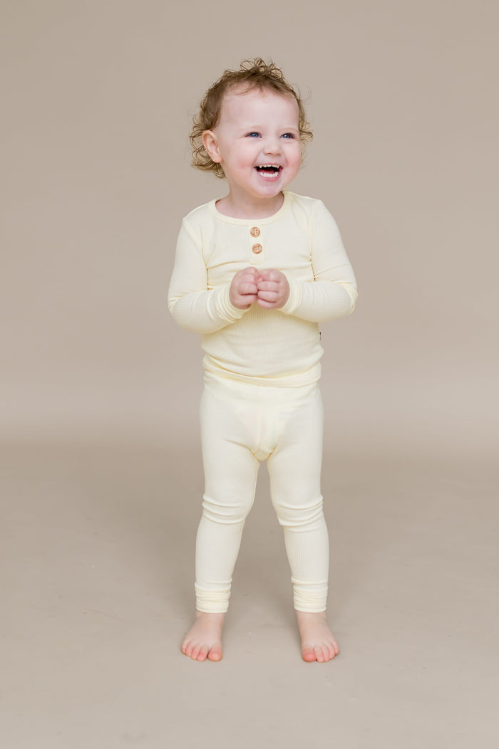 Smiling child standing wearing the Ribbed Henley Set in Chamomile