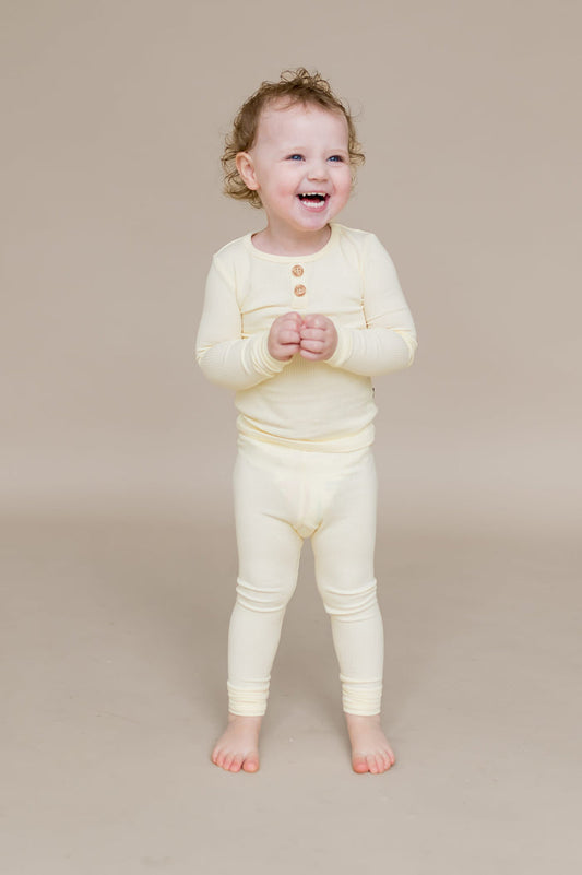 Smiling child standing wearing the Ribbed Henley Set in Chamomile