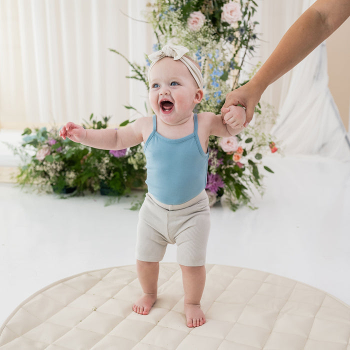 Infant wearing Kyte Baby Ribbed Biker Shorts in Oat