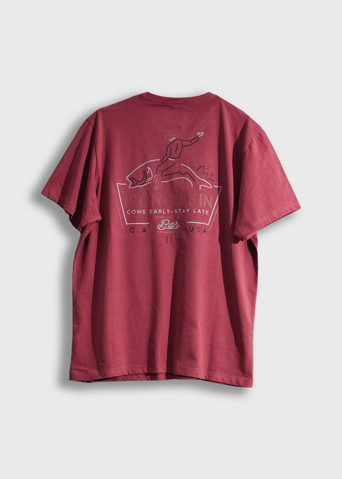 Red T-shirt with a graphic of a person surfing a fish, text "Iron & Resin, Come Early-Stay Late, CA, USA" on the back.