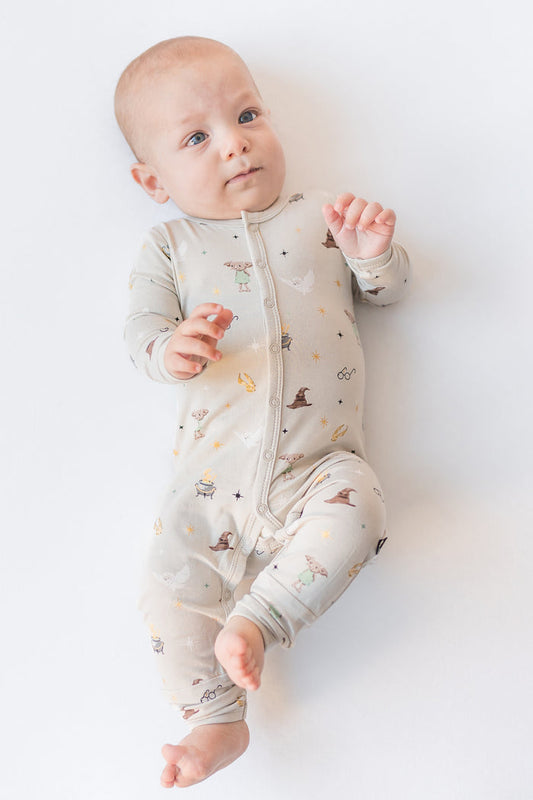 Baby wearing a cream snap romper with Harry Potter prints on a white background
