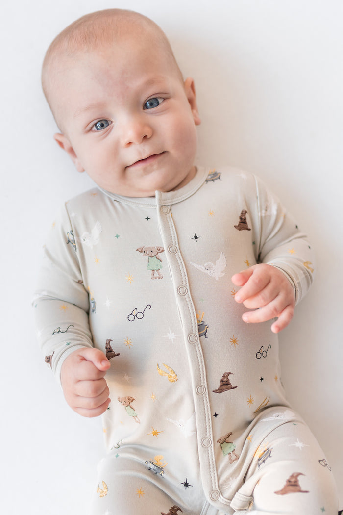 Baby wearing a Harry Potter patterned cream snap romper on a white background