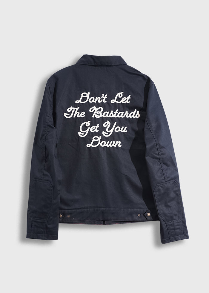 Navy jacket with bold white text: "Don't Let The Bastards Get You Down" on the back, conveying a strong motivational message.