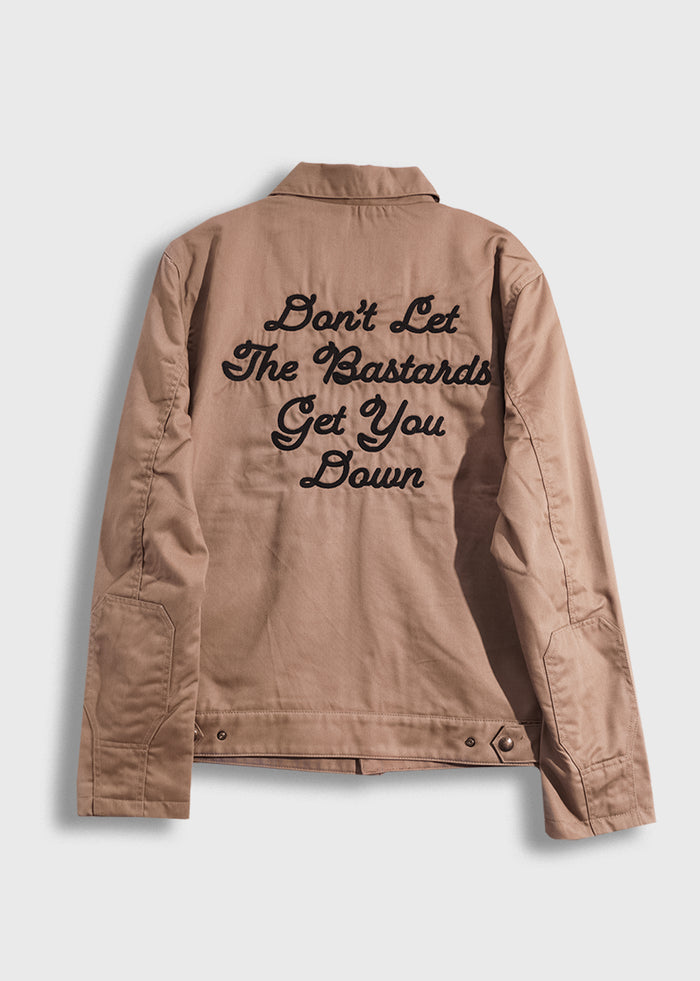Tan jacket with bold black text: "Don't Let The Bastards Get You Down" on the back, conveying a strong motivational message.
