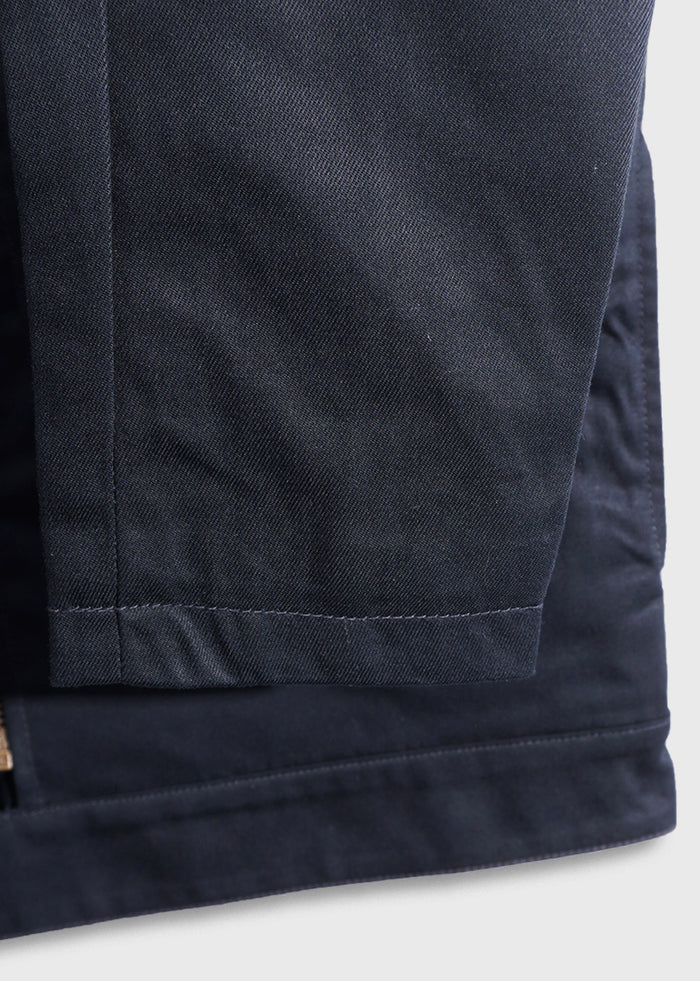 Close-up of a navy blue jacket hem, showcasing detailed stitching and fabric texture against a light background.