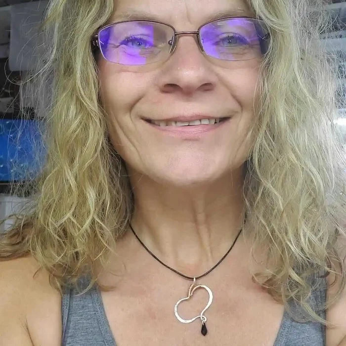 Sculpted Silver Butterfly Wing Child Abuse Survivor Necklace worn by a smiling woman with curly hair.
