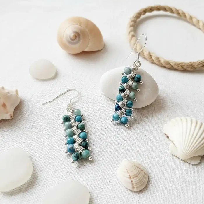 Seen On Jane The Virgin Silver Turquoise Wire Coil Earrings displayed alongside seashells and stones.