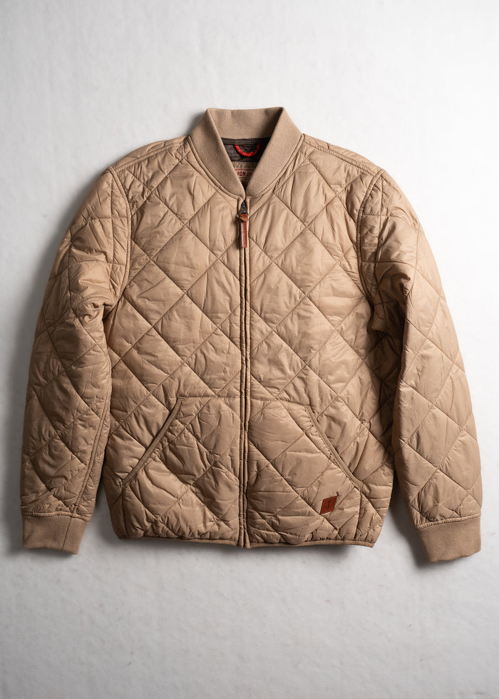 Tan quilted bomber jacket with ribbed collar and cuffs, featuring a front zipper and diamond pattern, laid flat on a white surface.