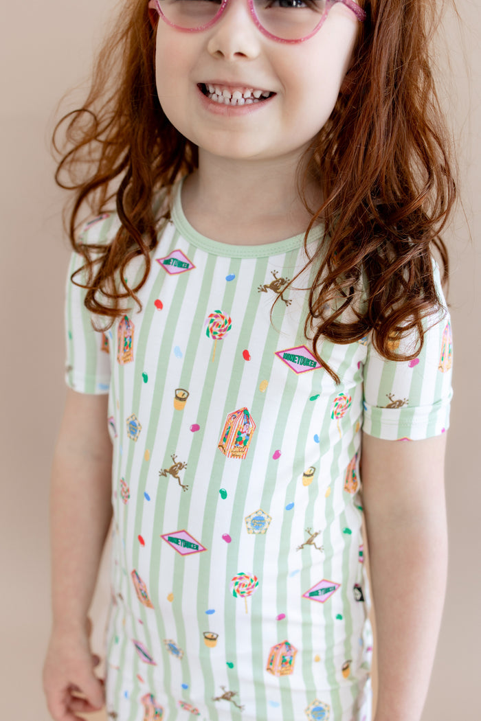 Child wearing a green and white striped short sleeve shirt with colorful Harry Potter patterns