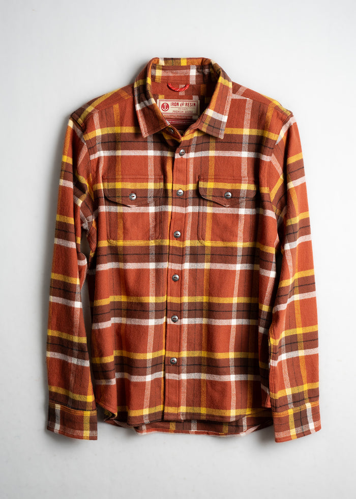 Orange, yellow, and brown plaid flannel shirt with buttons, two chest pockets, and a collar, displayed on a white background.