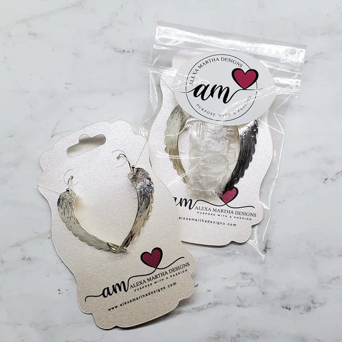 Silver Hammered Sculpted Angel Wing Earrings presented on packaging.