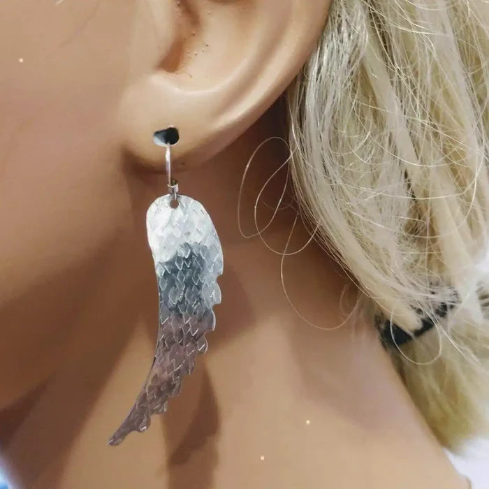 Silver Hammered Sculpted Angel Wing Earrings showcased on a mannequin's ear, reflecting light with a textured finish.